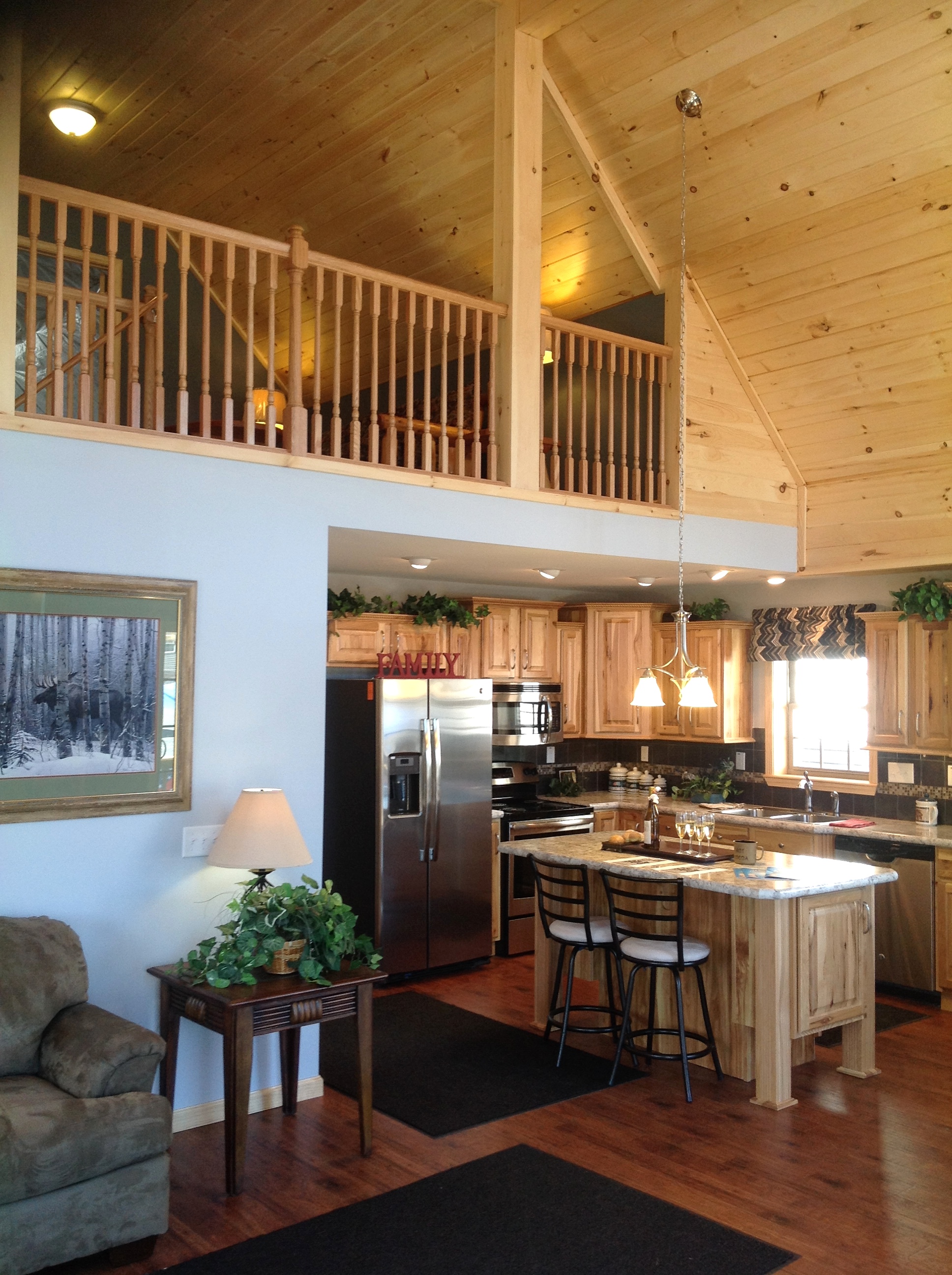 Vaulted loft with pine railing, overlooking kitchen.